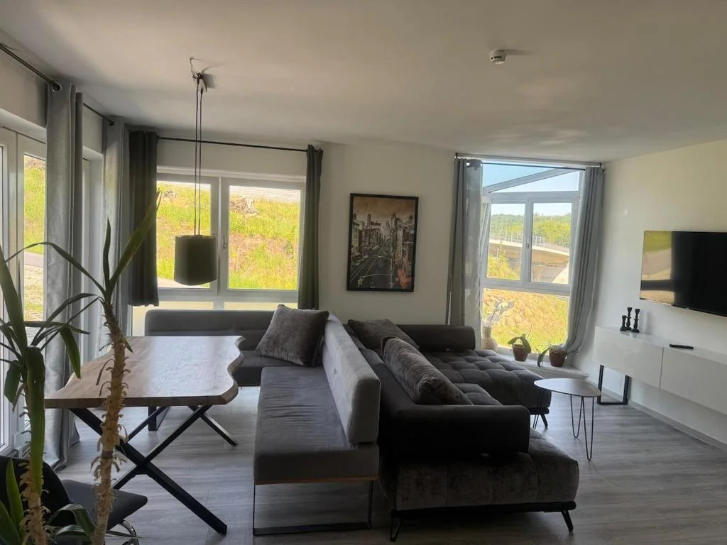 Wohnbereich mit Sofa, Esstisch und großen Fenstern — Casa Daniela Donau