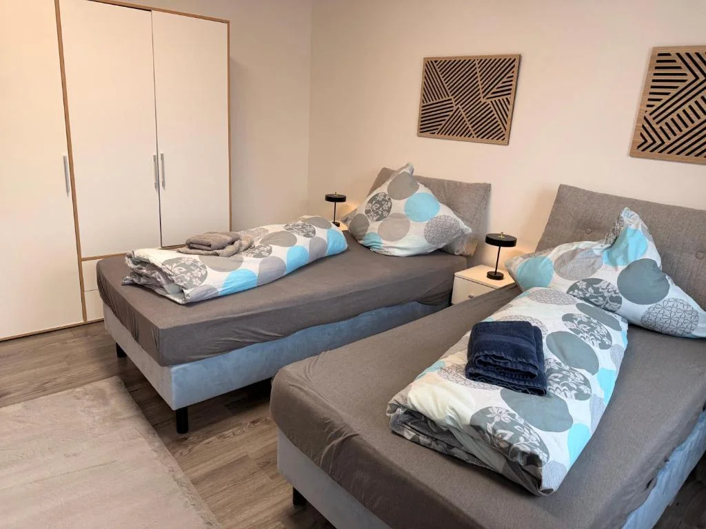 Zwei Einzelbetten mit blau-grauer Bettwäsche — Casa Daniela Residence